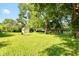 Spacious backyard featuring mature trees, lush green grass, outbuilding, and ample space for recreation at 7643 S Delaware St, Indianapolis, IN 46227