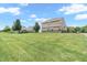 Wide backyard view showcasing the home's vinyl siding, manicured lawn, and surrounding trees at 793 Penny Ln, Pittsboro, IN 46167