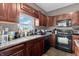 Close up of kitchen showing stainless steel sink, dark wood cabinets and black appliances at 793 Penny Ln, Pittsboro, IN 46167