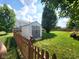 Backyard shed with gray doors and white siding surrounded by a green lawn and wooden fence at 8433 Vyners Ln, Avon, IN 46123