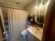 Cozy bathroom with shower-tub combination, round mirror, storage, and light leafy green and cream wallpaper at 9783 Lee Ct, Columbus, IN 47203