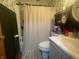 Small bathroom with shower-tub combination, striped curtain, commode, vanity, and light leafy green and cream wallpaper at 9783 Lee Ct, Columbus, IN 47203