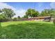 Brick home's backyard with a lush lawn, mature trees, and trampoline at 3331 Loral Dr, Anderson, IN 46013