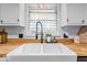 Close-up of a farmhouse sink with modern faucet, bright window, and butcher block countertop detail at 3331 Loral Dr, Anderson, IN 46013