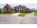 Stately brick home featuring a circular driveway and lush green lawn at 4499 W 131St St, Carmel, IN 46074