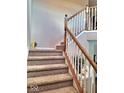 Carpeted staircase with white railing and oak trim leads to the upper level at 6343 Central Blvd, Whitestown, IN 46075