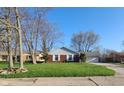 Classic brick home featuring a lush green lawn and attached garage at 3230 Meadowcrest Dr, Anderson, IN 46011