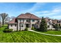 Beautiful two-story stone home featuring lush green lawn and mature trees under a bright, partly cloudy sky at 11492 Hanbury Manor Blvd, Noblesville, IN 46060