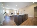 View of open-concept kitchen island with modern faucet, stainless steel dishwasher, and seamless flow into the living room at 7942 Beaumont Green Pl, Indianapolis, IN 46250