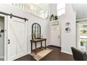 Bright foyer with dark wood floors, a sliding barn door, and a view of the open staircase at 11193 Harriston Dr, Fishers, IN 46037