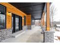 Spacious covered porch with wooden posts and gray brick base; snowy landscape visible at 2101 N Wolf Cv, Martinsville, IN 46151