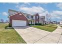 View of the home and driveway; two-story home with brick accents and a well-maintained lawn at 11851 Fawn Crest Dr, Indianapolis, IN 46235