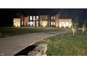 Night view of a modern mixed material home featuring exterior lighting and a long driveway at 9700 Windy Hills Dr, Zionsville, IN 46077