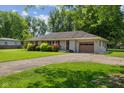 Inviting exterior showcasing well-maintained landscaping, a single-car attached garage, and a mature tree in the yard at 105 Tulip Dr, Indianapolis, IN 46227
