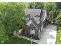 Aerial view of a brick home with mature trees, a spacious driveway, and manicured landscaping at 11633 Trail Ridge Pl, Zionsville, IN 46077