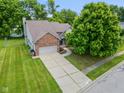Aerial view of home showing large lawn, mature tree and an attached two car garage with brick accents at 1936 Broadmoor Ln, Columbus, IN 47203