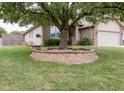 Exterior view of a well-manicured front yard with a large tree and brick-lined garden, adding character to the home at 5964 Laramie Trl, Columbus, IN 47203