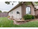 Landscaped side yard featuring manicured lawn, shrubs, garden beds, and a fence creating a private outdoor space at 5964 Laramie Trl, Columbus, IN 47203