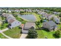 Aerial view of neighborhood homes with a tranquil pond and lush green lawns at 3335 Hurst St, Whiteland, IN 46184