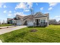 New construction, a lovely gray home with a two-car garage and a freshly planted tree in the front yard at 16920 Cattle Hollow Ln, Noblesville, IN 46060