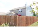 View of the backyard with a tall wood fence for privacy and a red umbrella at 882 Brookshire Dr, Franklin, IN 46131
