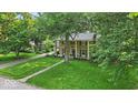 Beautiful stone home with mature trees, green lawn, and covered porch is a homebuyer's dream at 4807 Graceland Ave, Indianapolis, IN 46208