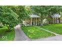 Traditional stone home with covered front porch, mature trees, and green lawn is an ideal home at 4807 Graceland Ave, Indianapolis, IN 46208