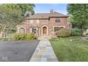 Charming brick home showcasing manicured landscaping, stone pathway, and a stately arched wood front door at 5650 N Meridian St, Indianapolis, IN 46208