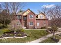 Charming red brick two-story home with a well-manicured lawn and mature trees at 8418 Mesic Ct, Indianapolis, IN 46278