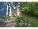 Charming blue home showcasing a stone accent, flower boxes on the porch and a landscaped garden at 327 Central Ave, Anderson, IN 46012