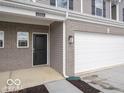 Close-up exterior featuring the garage, front door, brick accents and gray siding of the townhome at 6304 Wasco Dr, Whitestown, IN 46075