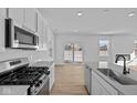 Bright, modern kitchen with stainless steel appliances, light countertops, and sleek white cabinets, with light wood-look flooring at 5143 Rolling Meadow Blvd, Indianapolis, IN 46237