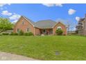 All-brick one-story house featuring a well-manicured front lawn, lovely landscaping and rocking chairs on the front porch at 603 Ophelia Dr, Avon, IN 46123