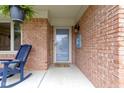 Inviting brick front porch with blue rocking chair and hanging plants beside a storm door at 603 Ophelia Dr, Avon, IN 46123