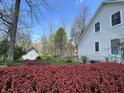 A secluded backyard featuring lush red bushes, mature trees, and a charming storage shed for tools and garden equipment at 1612 S Jeanne Ct, New Palestine, IN 46163