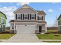 Traditional two-story home featuring gray siding, black shutters, a two-car garage, and a well-manicured lawn at 2260 Marjorie Way, Shelbyville, IN 46176
