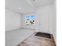 Bright entryway with grey carpet, wood-look floors, and a view of the backyard at 4779 E Shadowbrook Dr, Camby, IN 46113