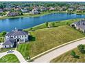 An aerial view of a lakefront property with a manicured lawn and stunning curb appeal in a lovely neighborhood at 1717 Beaufain St, Carmel, IN 46032