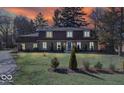 Dusk view of home with stone facade, well-lit windows, and manicured landscaping at 6906 Johnson Rd, Indianapolis, IN 46220