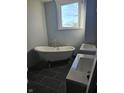 Bathroom boasts a clawfoot tub, dual sink vanity, gray ceramic tile, and a bright window at 201 W Walnut St, Waldron, IN 46182