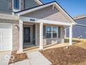 Covered porch entryway with gray siding, brick columns, and a dark door at 6036 Card Blvd, Indianapolis, IN 46221