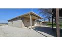 A detached garage with a covered area offers parking and extra storage, set on a gravel lot at 5861 S 100 W, Fountaintown, IN 46130