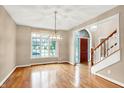 Bright dining room with hardwood floors, elegant chandelier, large window, and doorway to foyer at 6640 Greenridge Dr, Indianapolis, IN 46278
