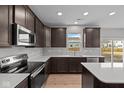 Modern kitchen featuring stainless steel appliances, dark wood cabinetry, white countertops, and a view of the backyard at 4186 Dutton Dr, Bargersville, IN 46106