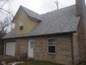 A side view of the brick home features an attached garage, and access door at 2021 N Graham Ave, Indianapolis, IN 46218