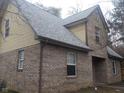A detailed view of the side of the brick home showing yellow vinyl siding on the second level at 2021 N Graham Ave, Indianapolis, IN 46218