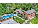 Aerial view of the backyard showcasing the pool, landscaped garden, and brick outbuildings with covered walkways at 2505 Riverside Dr, Columbus, IN 47201