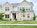 Charming two-story brick home featuring a well-manicured lawn and a welcoming entrance at 5778 W Commonview Dr, McCordsville, IN 46055