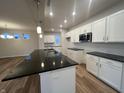Modern kitchen featuring white cabinets, stainless steel appliances, and an island with a black countertop at 12020 Gia Ct, Noblesville, IN 46060