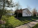 View of a side yard with green grass and various trees, with other homes visible in background at 8010 Philadelphia Dr, Fishers, IN 46038